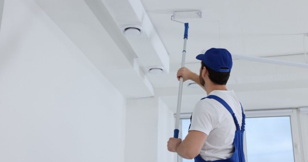 Peintre professionnel avec une perche téléscopique.