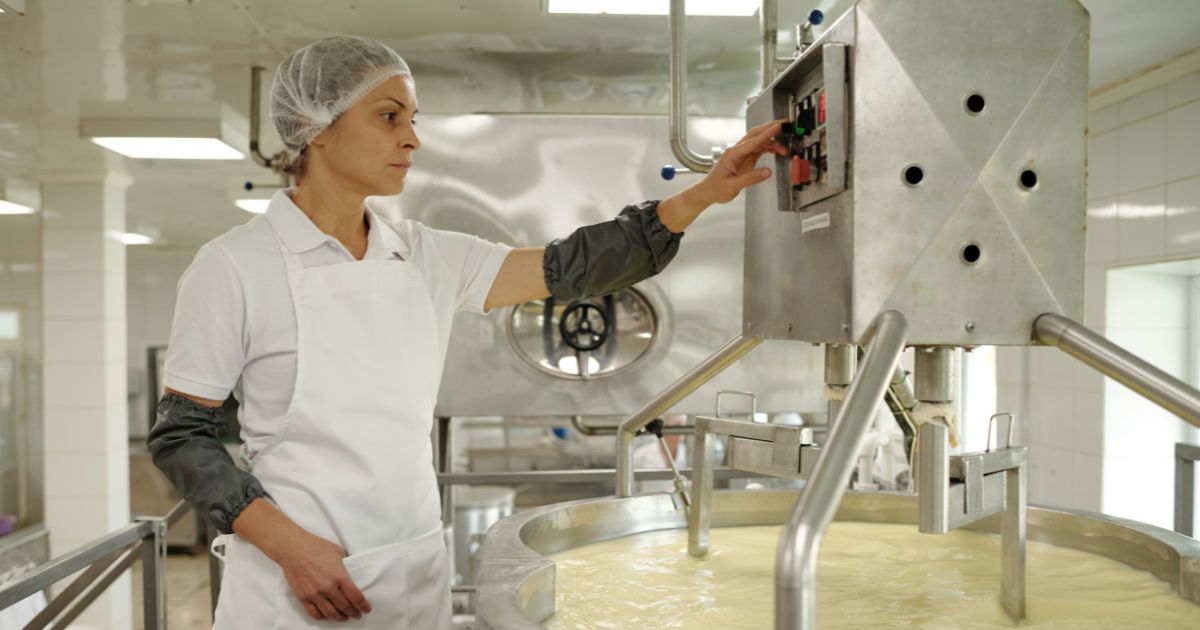 Femme en trani de préparer du fromage dans un atelier agro industriel stéril.
